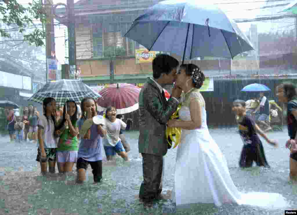 Ramoncito Campo kisses his wife Hernelie Ruazol Campo on a flooded street during a southwest monsoon that battered Manila, August 8, 2012. 