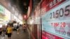 People walk past an electronic board showing the Hong Kong share index outside a local bank in Hong Kong, Monday, Aug. 24, 2015.