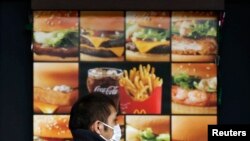 Seorang pria berjalan melewati papan iklan yang menunjukkan menu yang disajikan oleh restoran cepat saji McDonald's di salah satu gerai restoran di Tokyo, pada 16 Desember 2014. (Foto: Reuters/Issei Kato)