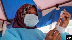 FILE - A nurse prepares to administer a vaccination against COVID-19, at a district health center in the low-income Kibera neighborhood of Nairobi, Kenya, Jan. 20, 2022.