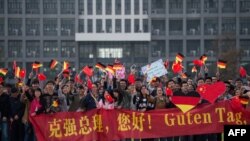 资料照：中国安徽省合肥市的德国大学学生们手持中德横幅和中德国旗等待德国时任总理默克尔的访问。 (2015年10月30日)