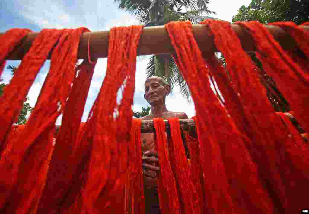 A worker hangs dyed yarns to dry at a textile mill on the outskirts of Agartala, India.