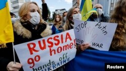 Irenyen ki abite Japon kenbe pannkat ak drapo nan men yo pandan yon manifestasyon pou denonse zak La Risi poze nan Ikren yo, tou pre Anbasad Ris la nan Tokyo, Japon, 23 Fevriye 2022. 