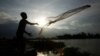 A construction worker casts a fishing net onto a flooded land following recent rain to catch fish on the outskirts of Phnom Penh, Cambodia, Thursday, June 11, 2020. (AP Photo/Heng Sinith)