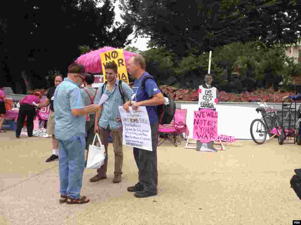 反对美国军事干预叙利亚的抗议人士向路过的行人与车辆展示抗议标语。