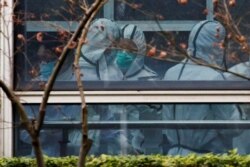 FILE - Members of the World Health Organization team, investigating the origins of the coronavirus disease, don personal protection suits during a visit at the Hubei Animal Epidemic Disease Prevention and Control Center in Wuhan, Feb. 2, 2021.