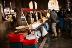 FILE - A fishmonger waits for customers in a barely empty street food market in Venice, Feb. 29, 2020.