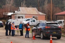 FILE - Medical workers and volunteers administer the coronavirus vaccine at a drive-through clinic in Mora, N.M., April 20, 2021. New Mexico is offering cash lottery prizes in a bid to increase vaccination rates.