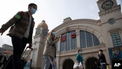 Travelers with their luggage walk past the Hankou railway station on the eve of its resuming outbound traffic in Wuhan in central China's Hubei province on Tuesday, April 7, 2020. Starting Wednesday, residents of Wuhan will be allowed to once again…