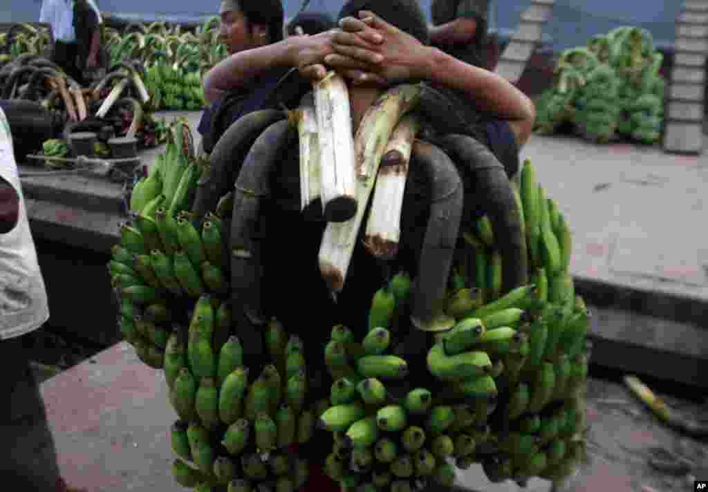 A worker carries bunches of bananas on his shoulder after being unloaded from a ship at a jetty in Rangoon, Burma.