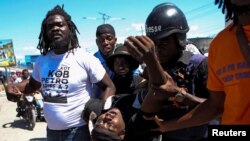 Moun ede yon jounalis ki blese pa bal pandan li tap kouvri yon manifestasyon nan Potoprens. Jounalis la mouri nan wout pou'l al lopital, 23 Fevriye, 2022. 