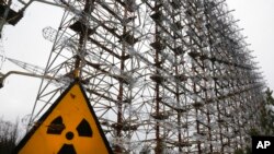 FILE - A Soviet-era top secret object Duga, an over-the-horizon radar system once used as part of the Soviet missile defense early-warning radar network, is seen behind a radioactivity sign in Chernobyl, Ukraine, on Nov. 22, 2018. 