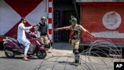 印度准军事士兵在铁丝网路检查站查问一名骑摩托车的人。（2017年7月7日）