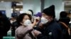A woman wearing a mask to prevent contracting the coronavirus adjusts her husband's mask as they wait to check in at Incheon International Airport in Incheon, South Korea, March 19, 2020. REUTERS/Kim Hong-Ji