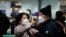 A woman wearing a mask to prevent contracting the coronavirus adjusts her husband's mask as they wait to check in at Incheon International Airport in Incheon, South Korea, March 19, 2020. REUTERS/Kim Hong-Ji