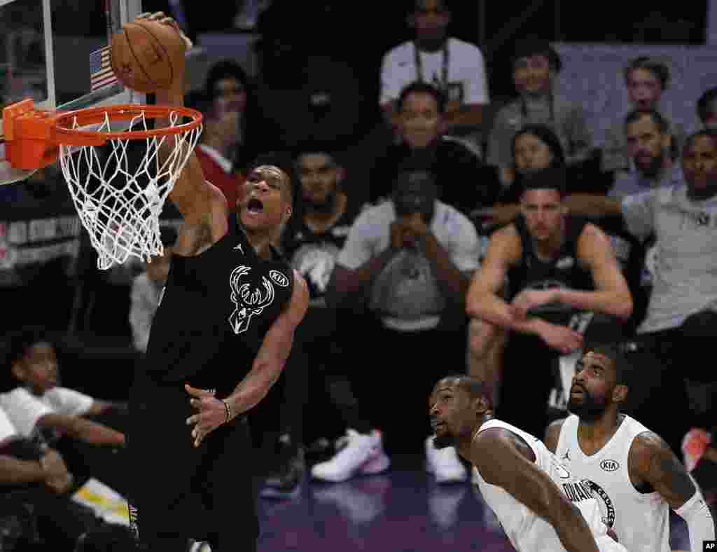 L&#39;attaquant de l&#39;équipe Stephen Giannis Antetokounmpo, des Milwaukee Bucks pénètre à l&#39;intèrieur contre Kevin Durant des Golden State Warriors de l&#39;équipe LeBron et passe Kyrie Irving, des Celtics de Boston, pour marquer un panier, le 8 février 2018.