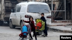 孩子们在被叙利亚反对派控制的阿勒颇省里推着放有集装箱的婴儿车(2016年12月12日)