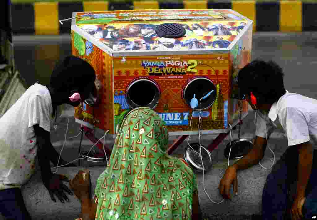 Seorang wanita India dan dua anak laki-lakinya menonton trailer dari film Bollywood &quot;Yamla Pagla Deewana 2&quot; di Mumbai, India.
