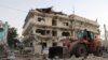 FILE - A backhoe loader clean the street outside the Maka Al-Mukarama hotel in the Somalia capital, Mogadishu on March 1, 2019 after a car bomb exploded, killing at least five people and wounding 25 others. 