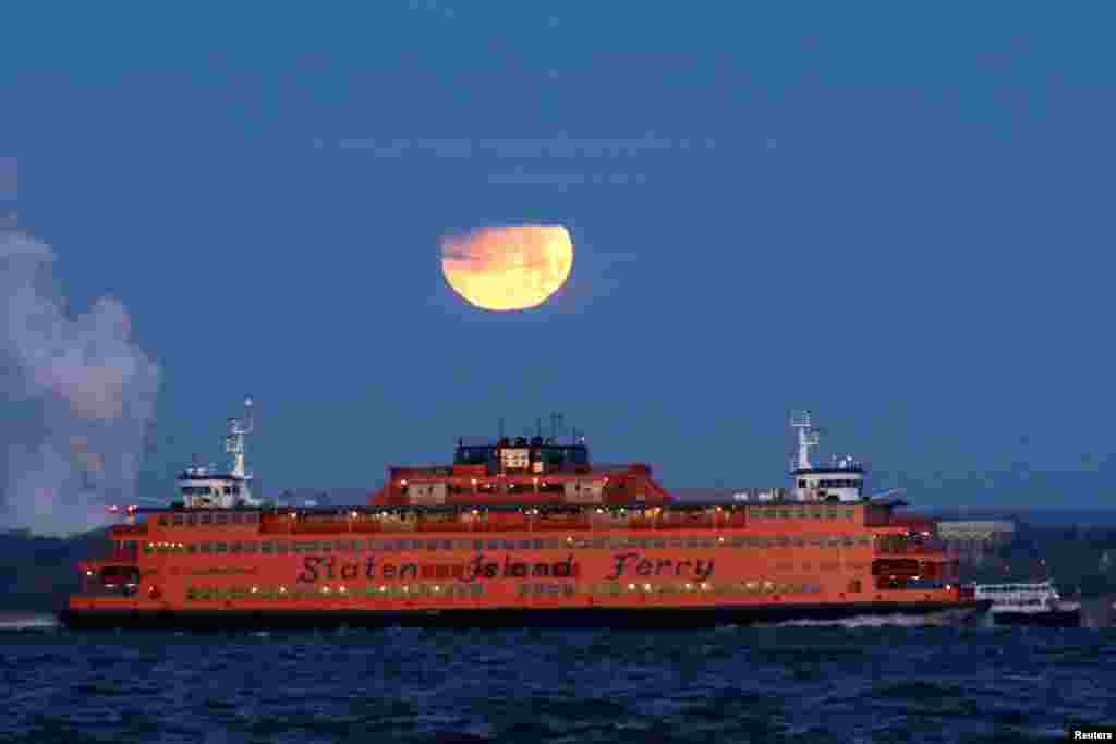 2018年1月31日，在美国纽约布鲁克林眺望史坦顿岛渡口的红黄两色的&ldquo;超级月&rdquo;月落。