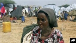 A woman sits with her baby in an open area near a camp in Mogadishu, Somalia, earlier this summer. Famine and drought have made bad conditions worse in the area.