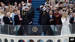 도널드 트럼프 미국 45대 대통령과 마이크 펜스 부통령, 물러나는 바락 오바마 대통령이 20일 워싱턴 국회의사당에서 열린 트럼프 대통령 취임식에서 다른 참석자들과 함께 잭키 에반초가 부르는 미국 국가를 듣고 있다.