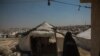 A woman walks among the thousands of tents at Al-Hol Camp. Here, the Islamic rules implemented by IS are still followed as they were under the group, Aug. 26, 2019. (Yan Boechat/VOA) 