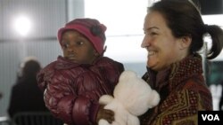 Seorang ibu warga Perancis menggendong anak adopsinya dari Haiti di bandara Roissy, Paris.