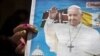 A churchgoer holds a copy of the Catholic Mirror newspaper showing a photograph of Pope Francis, after mass outside the Holy Family Minor Basilica in downtown Nairobi, Kenya, Nov. 22, 2015.