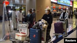 中国黑龙江省会哈尔滨机场的旅客为防疫戴着口罩。（2020年4月11日）