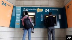 Para nasabah Bank Siprus menggunakan ATM di ibukota Nicosia (27/3). Siprus membatasi jumlah transfer uang nasabah dari Siprus ke negara lain. 
