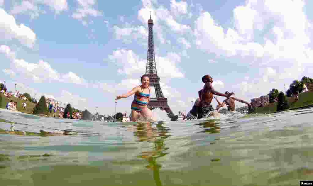 Youth cool off in a fountain of the Trocadero Square in front of the Eiffel Tower on a warm summer afternoon in Paris. 
