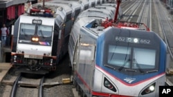 资料照片：一列美铁公司的火车沿着东北走廊铁路线行驶经过一列新泽西运输公司的火车。（2016年3月12日）