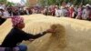 Farmers rearrange a pile of rice after dumping them on the ground outside a Bank for Agriculture and Agricultural Cooperatives in Bangkok, Thailand, during a rally demanding the Yingluck administration resolve delays in payment from the rice pledging scheme, March 11, 2014.