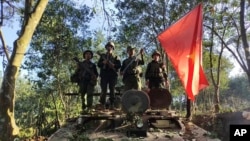 资料照片：缅甸民族民主同盟军成员在缴获的一辆缅甸陆军装甲车上举旗合影。（2023年10月28日）