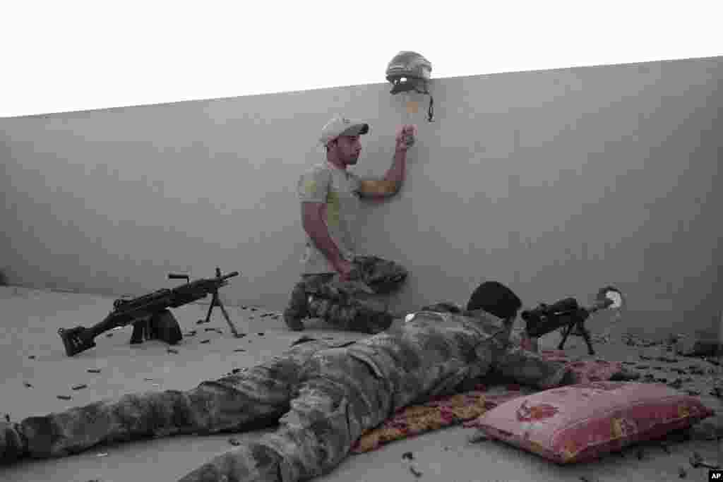 Tentara Irak memegang helm sebagai jebakan (tipuan) sementara rekannya siap menembak ke arah posisi militan ISIS di Gogjali, kota Mosul bagian timur.