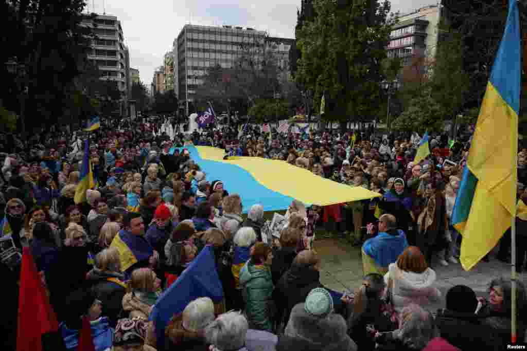 Афины, Греция Члены украинской общины и другие участники демонстрации против российского вторжения несут гигантский украинский флаг, 23 февраля 2025 года