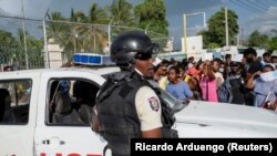 资料照片：在海地首都太子港，海地国家警察守卫着美国大使馆的入口。在总统莫伊斯遭暗杀身亡后，一些海地民众聚集在美国大使馆门口寻求庇护。（2021年7月9日）