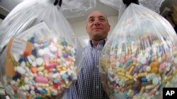 Detektif tindak pidana narkotika, Ben Hill, dari Kepolisian Baberton memperlihatkan obat-obatan opioid yang siap dimusnahkan, di Baberton, Ohio, 16 Oktober 2019. (Foto: Keith Srakocic/AP)