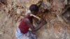 FILE - A woman rock-crusher hits rocks with a hammer in a quarry in Maroua, Cameroon, June 16, 2016.
