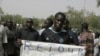 A man carries a sign reading 'Return to constitutional order,' as people gather in protest against the recent military coup, in Bamako, Mali on Monday, March 26, 2012.