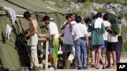 Des hommes se rasent, se brossent les dents et se préparent pour la journée dans un camp de réfugiés sur l'île de Nauru, le 21 septembre 2001.