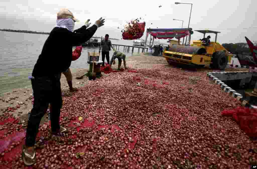 Seorang pekerja melemparkan karung bawang merah ke mesin penggiling untuk dihancurkan. Sekitar 9 (sembilan) ton bawang merah dan bawang putih yang diimpor secara gelap dari Malaysia dihancurkan petugas kantor Bea Cukai di kota Belawan, Sumatera Utara.