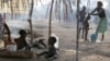 Children sit outside their family's tent as a neighbor bathes her son in a camp housing more than 2,600 Ivorian refugees in Solo Town, near Zwedrou, Liberia, May 25, 2011 (file photo).