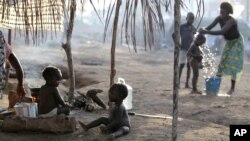 Children sit outside their family's tent as a neighbor bathes her son in a camp housing more than 2,600 Ivorian refugees in Solo Town, near Zwedrou, Liberia, May 25, 2011 (file photo).