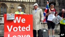 Pro Brexit demonstrators hold a placard outside the Houses of Parliament, in London, Sept. 5, 2019.
