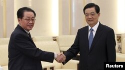China's President Hu Jintao (R) shakes hands with Jang Song Thaek, Chief of the Central Administrative Department of the Workers' Party of Korea, in Beijing, August 17, 2012.
