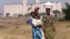 Malawian women walk past empty grain silos in the capital Lilongwe.