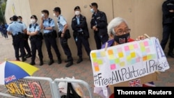 A pro-democracy supporter holds a sign calling for the release of all political prisoners outside Tin Shui Wai police station in Hong Kong, March 22, 2021.