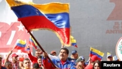 Presiden Nicolas Maduro melambaikan bendera merayakan peringatan kebangkitan revolusi "Caracazo"; dalam pidatonya ia mengumumkan penangkapan pilot AS yang diduga melakukan spionase, 28 Februari 2015.
